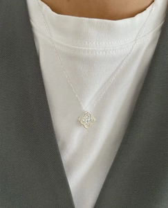 Detail of S925 silver four-leaf clover pendant necklace worn with a blazer
