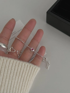 Close-up of pink heart gemstone bracelet and silver rings on a model in knitwear