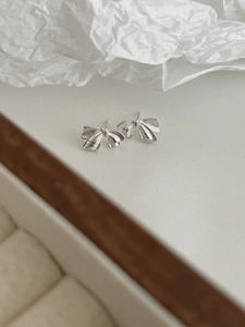 Vue détaillée des boucles d'oreilles nœud argentées avec texture métallique fine