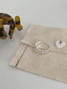 Close-up of S925 sterling silver beaded open ring on a soft linen fabric background