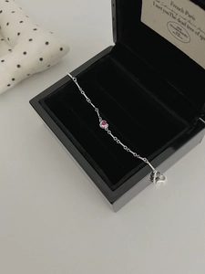 Detail of silver chain bracelet with heart red stone in a black jewelry gift box