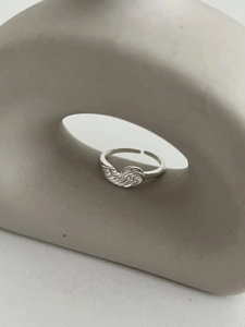 Détail d'une bague ajustable en argent 925 torsadé sur un support géométrique chic