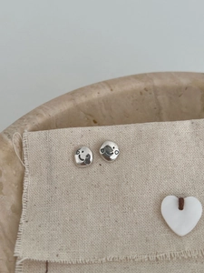 Dettaglio degli orecchini a lobo minimalisti S925 in argento smiley su lino beige