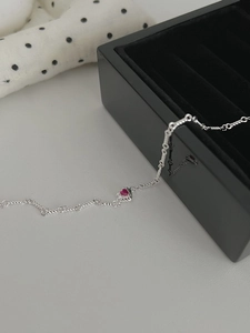 Macro detail of S925 silver twist chain with a vibrant red heart-shaped gemstone