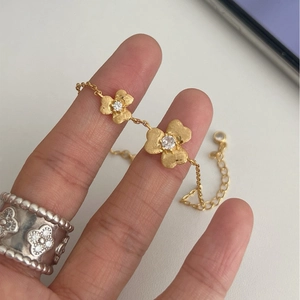 Frosted gold flower bracelet with crystal petals and engraved silver clover pattern ring