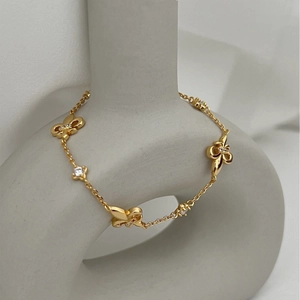 Elegant gold butterfly bracelet with pavé white crystals on a minimalist gray pedestal