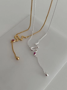 Detail of minimalist S925 silver snake necklaces with red stone in gold and silver finish