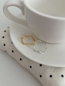 Detailed view of textured irregular gold and silver open rings on a ceramic saucer