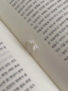 Detail of silver shell-shaped textured ring resting on an open book for a minimalist look