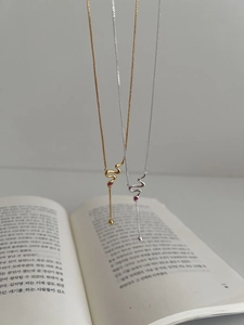 Detail of S925 silver snake necklaces with red zircons and long elegant tassels