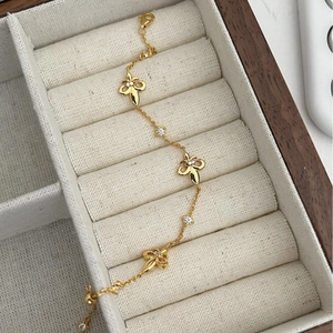 Elegant gold fleur-de-lis bracelet with white zircon accents in a wooden jewelry box