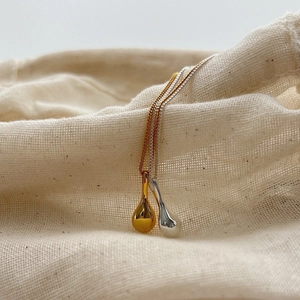 Elegant gold and silver S925 sterling silver teardrop pendant necklaces on linen background