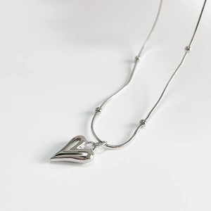 Minimalist silver heart pendant necklace with beaded snake chain on white background