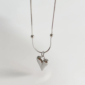 Detailed view of a silver snake chain necklace featuring a polished heart pendant