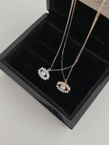 Détail macro de colliers œil en or et argent avec zircons dans un écrin à bijoux noir