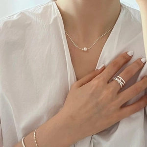 Minimalist silver pearl necklace with multilayer crossover ring on model