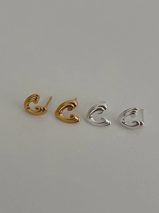 Macro shot of silver and gold C-shaped earrings with textured ripple finish