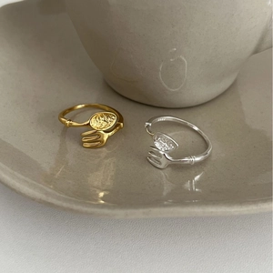 Unique fork and spoon open rings in silver and gold plating on a ceramic saucer