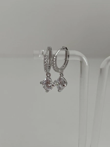 Détail macro de boucles d'oreilles en argent s925 avec pendentif moissanite à quatre griffes