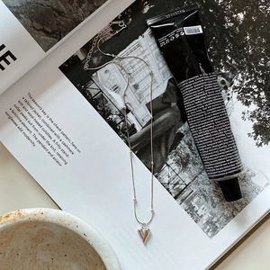 Detail of silver heart pendant necklace with bead chain and lobster clasp on magazine