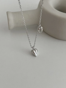 Detailed macro shot of a minimalist 3D double heart pendant in polished 925 silver