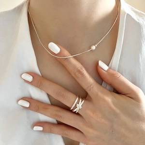 Elegant 925 sterling silver snake chain necklace with pearl and layered knot ring on a model