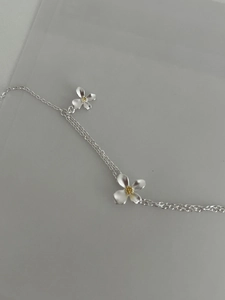 Gros plan d'un bracelet à double chaîne argentée avec des breloques marguerites bicolores