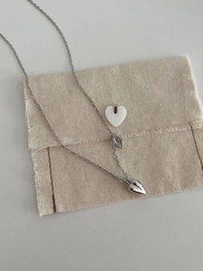Detail of a 925 sterling silver double heart necklace on a beige textured cotton bag