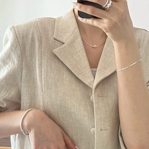 Minimalist pearl necklace and silver jewelry set worn on a linen suit for a modern look