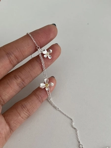 Gros plan d'un bracelet en argent avec deux breloques fleurs mates et cœurs jaunes