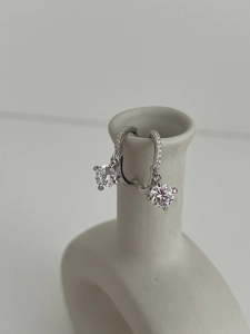 Vue macro de boucles d'oreilles en argent avec moissanite et pavé de cristaux sur un vase