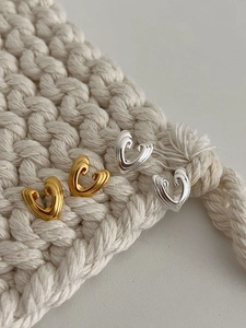 Detailed view of gold and silver heart studs on a minimalist white knitted texture