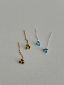 Detailed view of gold and silver flower earrings with green and blue enamel petals