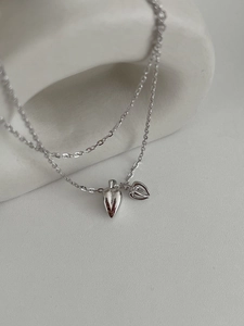 Close-up of double heart pendant necklace with solid and hollow charms on stone stand