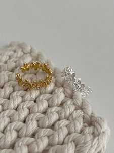 Macro shot of silver and gold daisy flower rings with micro-pave crystals on white knit