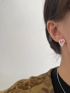 Detail shot of heart-shaped S925 silver earring with blue zircon on female model