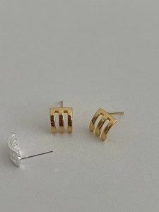 Macro view of three-claw geometric arc studs in polished silver and gold finish