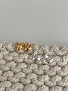 Detailed view of 3D heart stud earrings in polished gold and silver finishes on knit