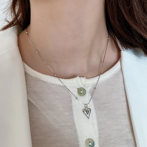 Close-up of polished silver heart pendant on beaded snake chain necklace for women