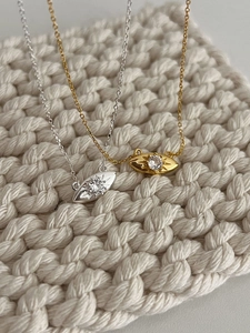 Gros plan de colliers en argent et or avec zircons étincelants sur un tricot blanc