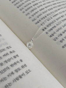 Detailaufnahme der S925 Silber Sonnenblumen Halskette auf offenen Buchseiten