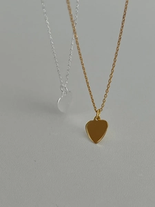 Close-up of minimalist gold and silver heart pendant necklaces with delicate chains