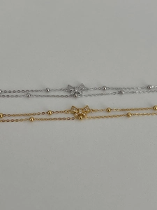 Detail of silver and gold double-layered bow bracelets with sparkling zircons