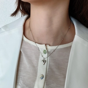 Detail of silver heart pendant necklace on model with polished bead chain and sleek finish