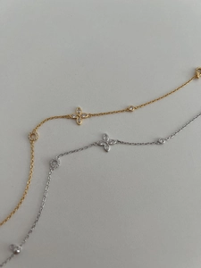 Detail of silver and gold bracelets with zircon-inlaid clover pendants and fine chain link
