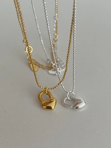 Dettaglio di collane con cuore in argento S925 in tonalità oro e argento a catena