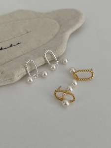 Detail view of 925 silver and gold twist hoop earrings with elegant white pearls