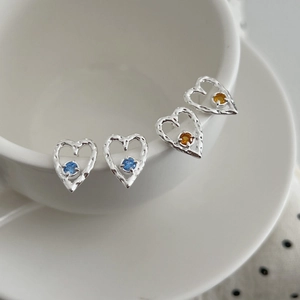 S925 silver heart stud earrings with blue and orange zircon gems on white ceramic cup