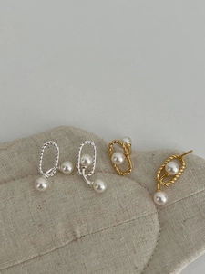 Detailed close-up of 925 silver and gold twist hoop earrings with dangling pearls