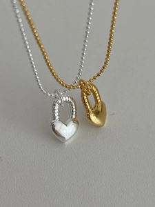 Dettaglio macro di ciondoli a cuore in oro e argento con trama a spirale su catena
